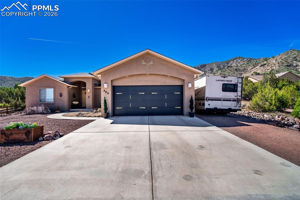 Image 3 of 50: Ranch-style house featuring a mountain view, driveway, stucco siding, and a