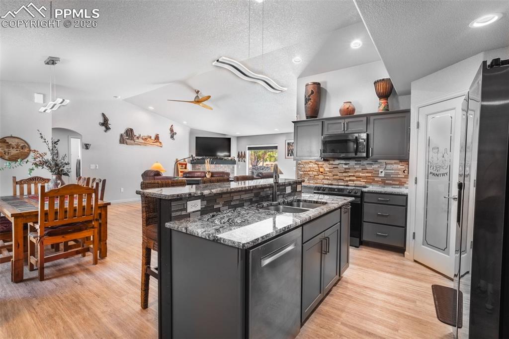 Image 6 of 50: Kitchen with dark stone countertops, open floor plan, a center island with 