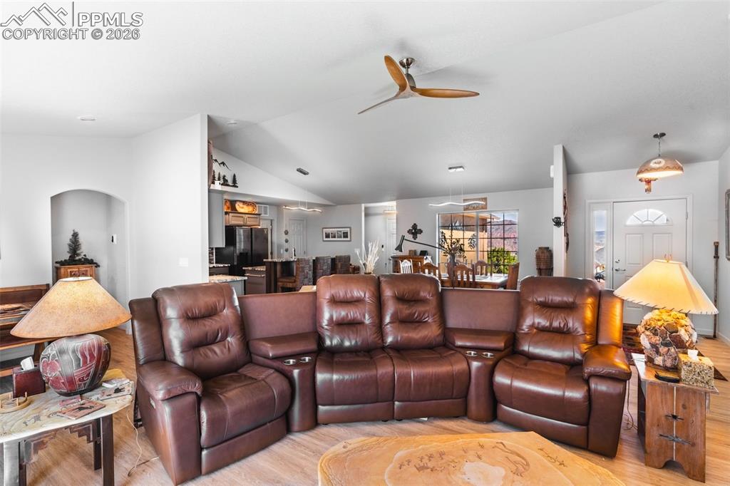 Image 9 of 50: Living room with vaulted ceiling, light wood-type flooring, and a ceiling f