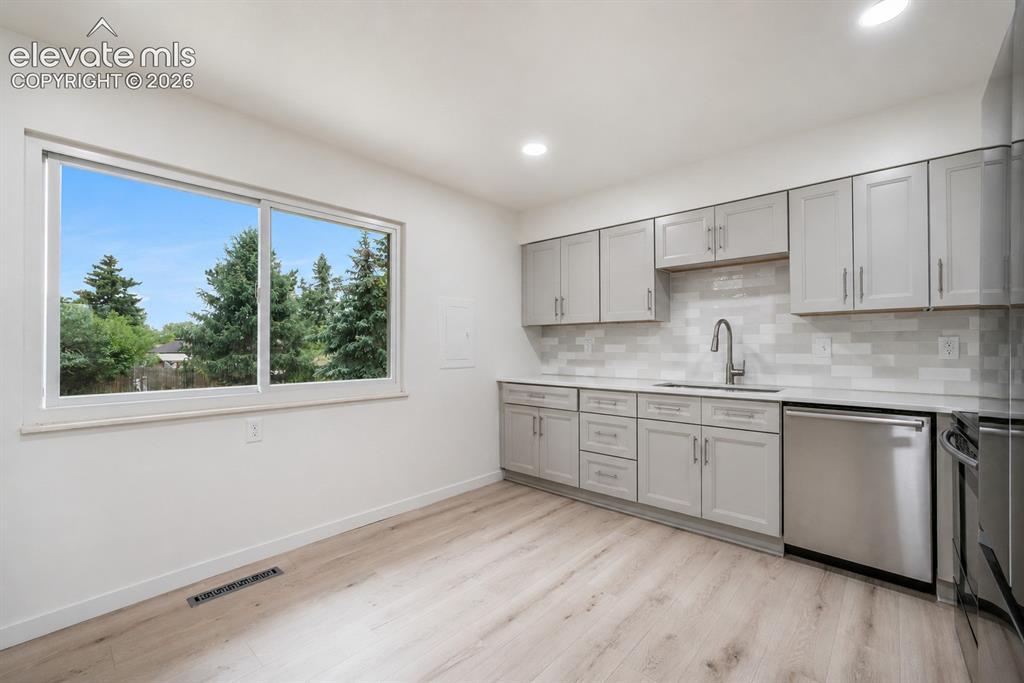 Image 11 of 47: Modern kitchen featuring light gray cabinetry, stainless steel appliances,