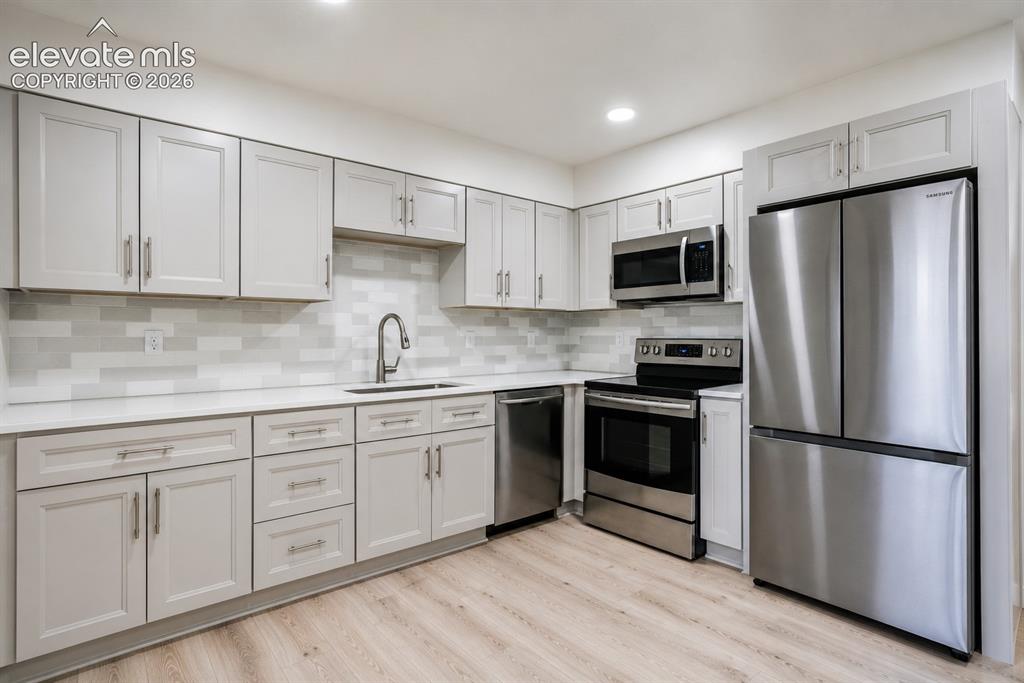 Image 12 of 47: Modern kitchen featuring light wood-finish flooring, light gray shaker-styl