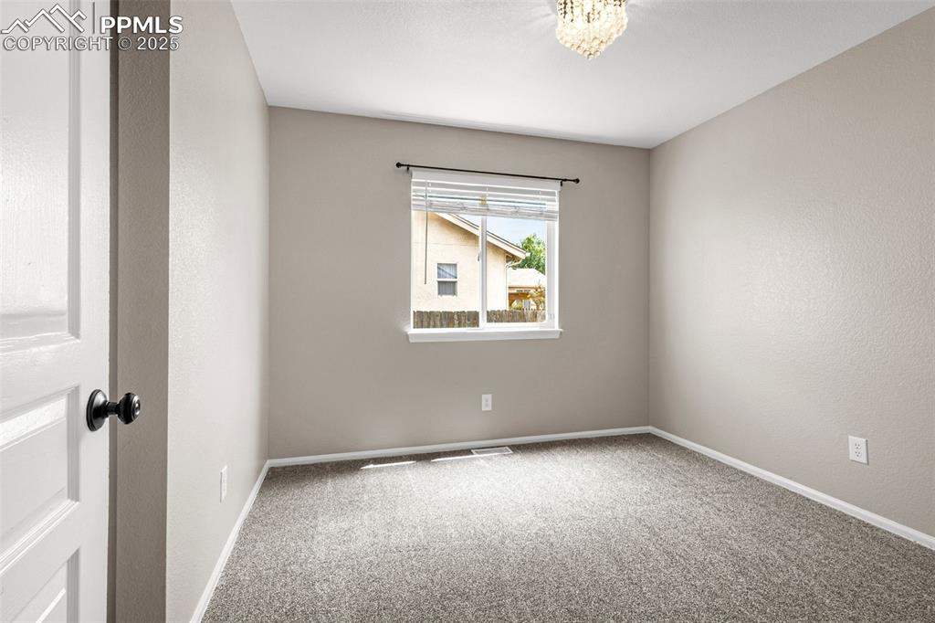 Image 14 of 38: Spare room with carpet flooring and a chandelier