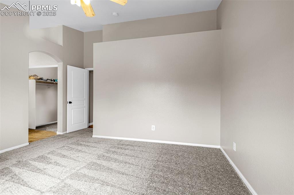 Image 15 of 38: Unfurnished bedroom featuring carpet, a walk in closet, arched walkways, an