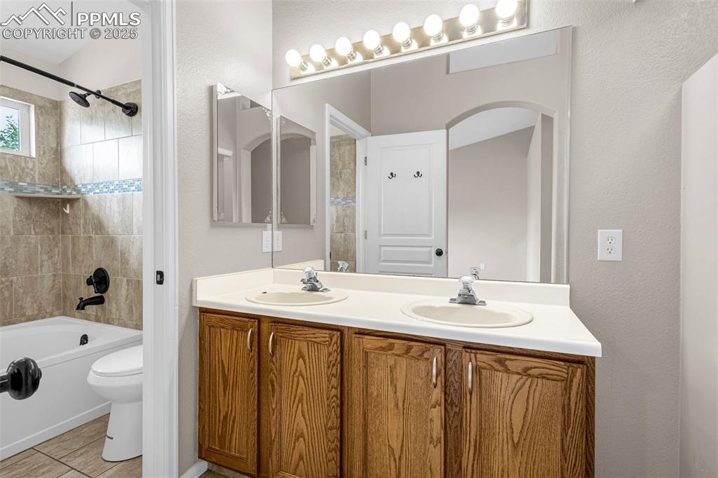 Image 17 of 38: Bathroom with double vanity, bathing tub / shower combination, and tile pat