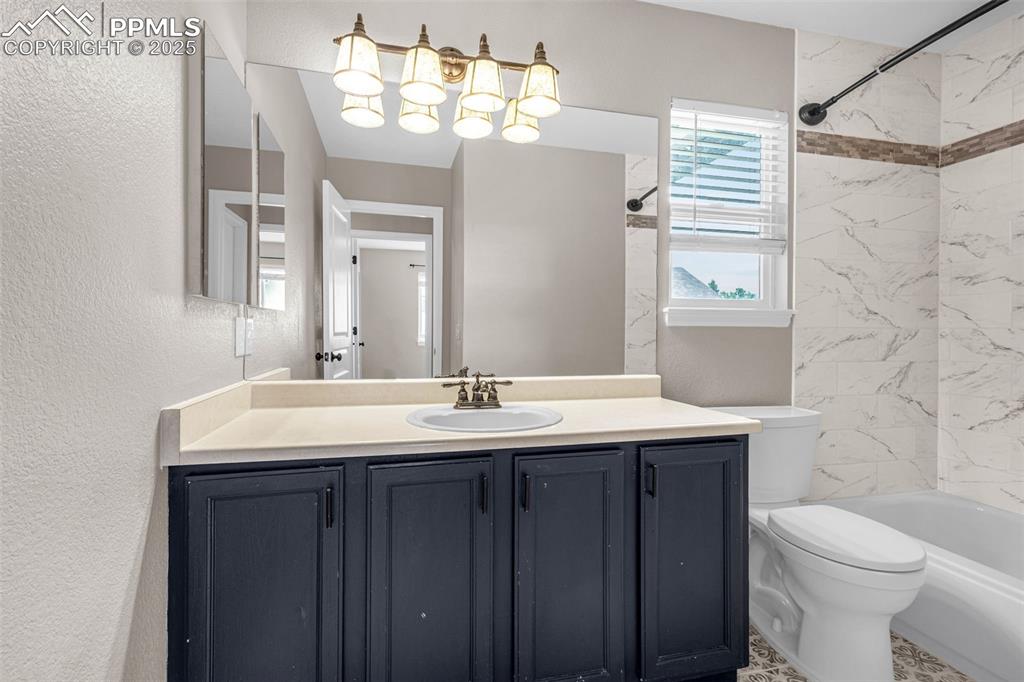 Image 19 of 38: Bathroom featuring a textured wall, vanity, and bathtub / shower combinatio