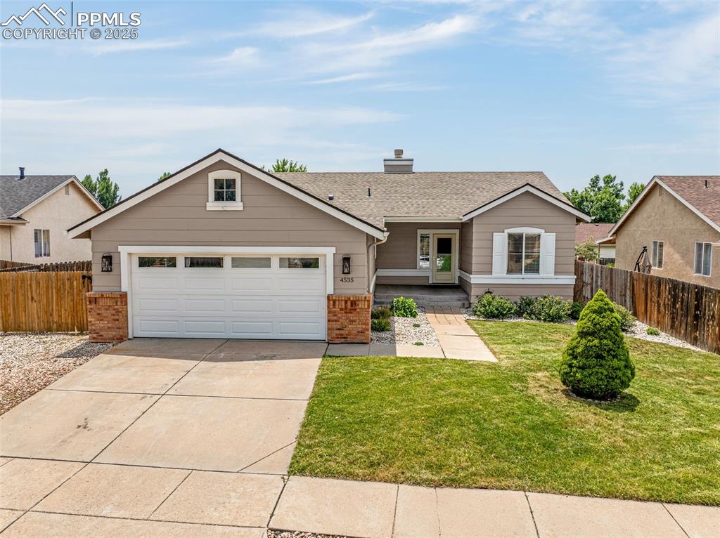 Image 2 of 38: Single story home with concrete driveway, brick siding, a chimney, and an a