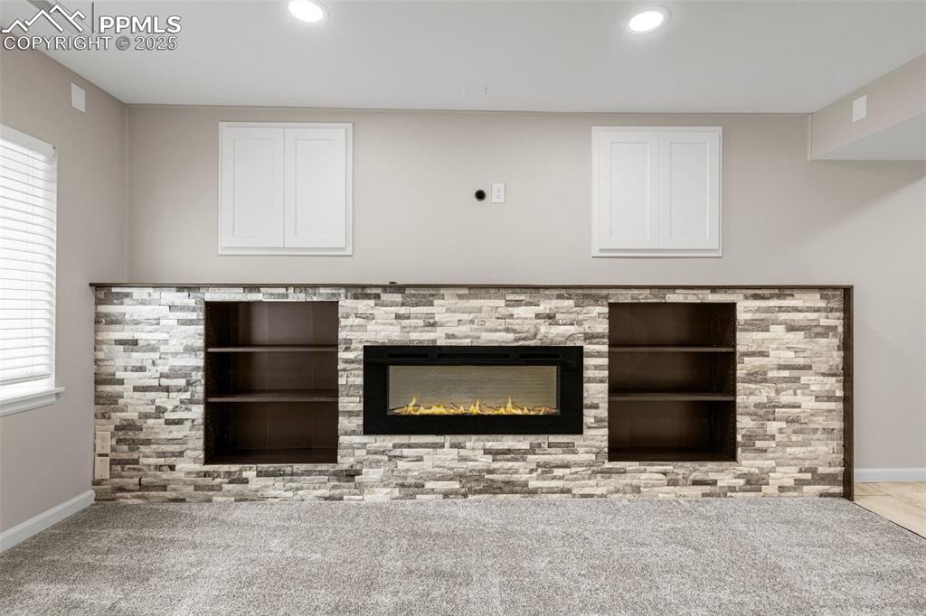 Image 24 of 38: Detailed view of recessed lighting, carpet floors, and a glass covered fire