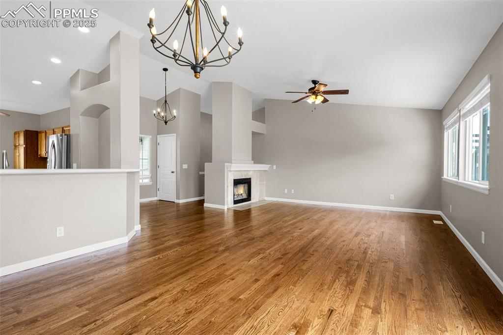 Image 5 of 38: Unfurnished living room with a chandelier, ceiling fan, wood finished floor