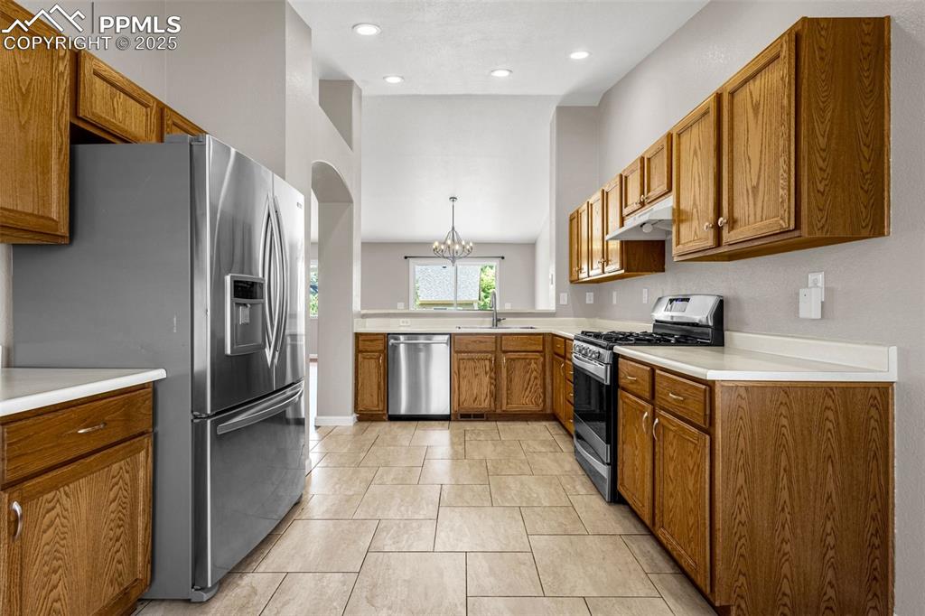 Image 6 of 38: Kitchen with appliances with stainless steel finishes, brown cabinetry, a c