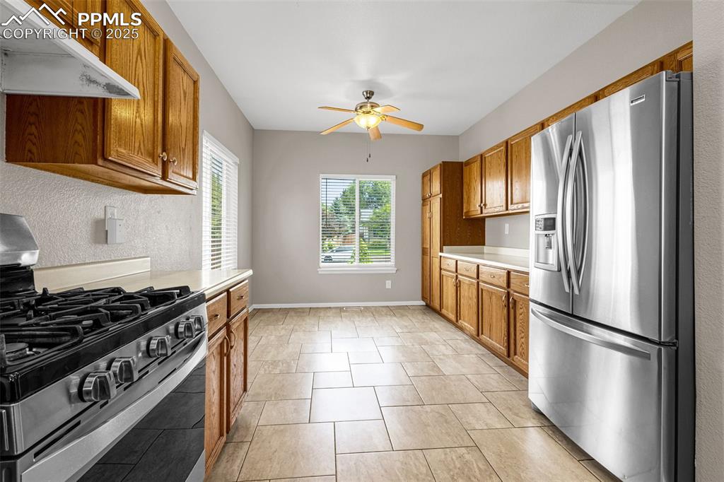 Image 8 of 38: Kitchen with appliances with stainless steel finishes, a ceiling fan, under