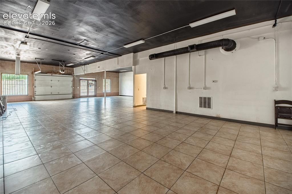 Image 10 of 50: Expansive open-concept space featuring large format tile flooring, roll-up 