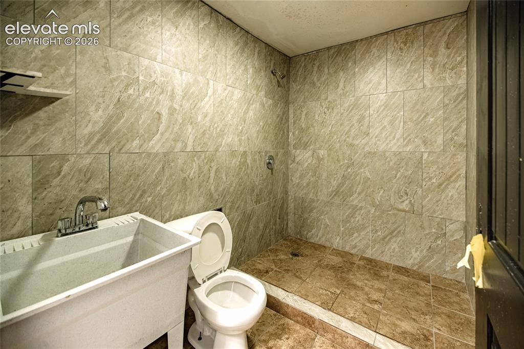 Image 15 of 50: Tiled shower surround with a fixed showerhead, single-handle shower control