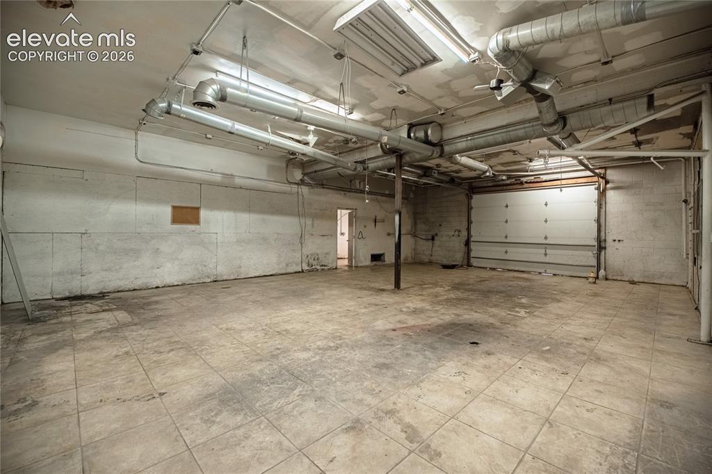 Image 20 of 50: Open space featuring concrete block walls and square floor tiles