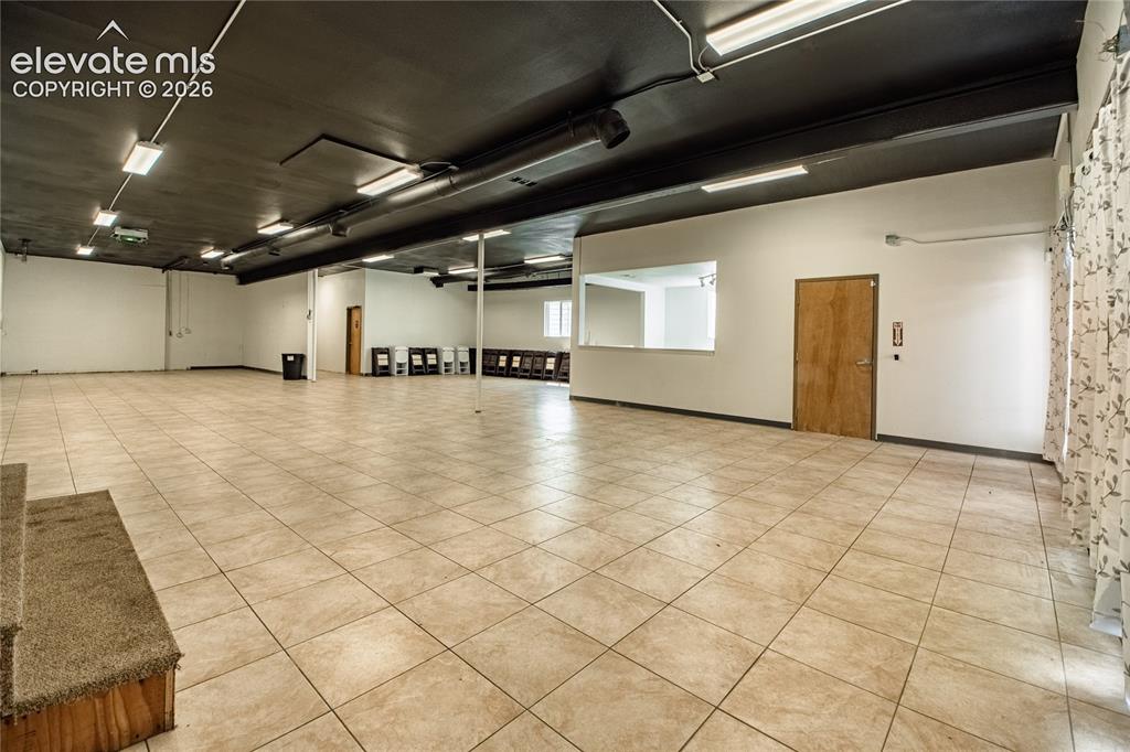 Image 22 of 50: Expansive open space featuring tile flooring, a dark finished ceiling, rece
