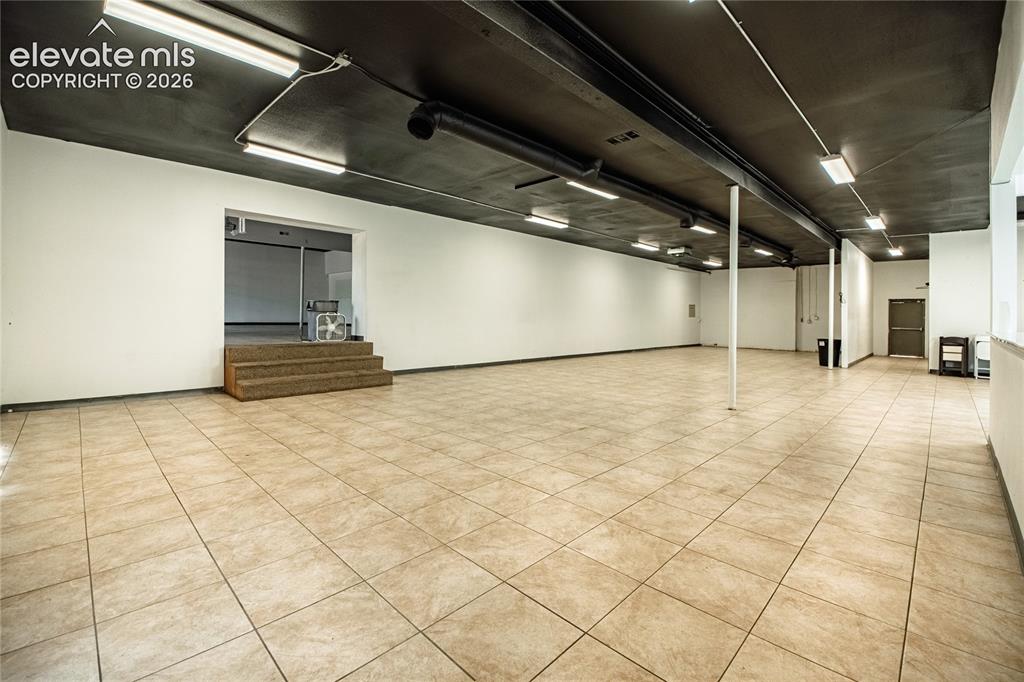 Image 23 of 50: Expansive open-concept space featuring neutral-toned tile flooring, white w
