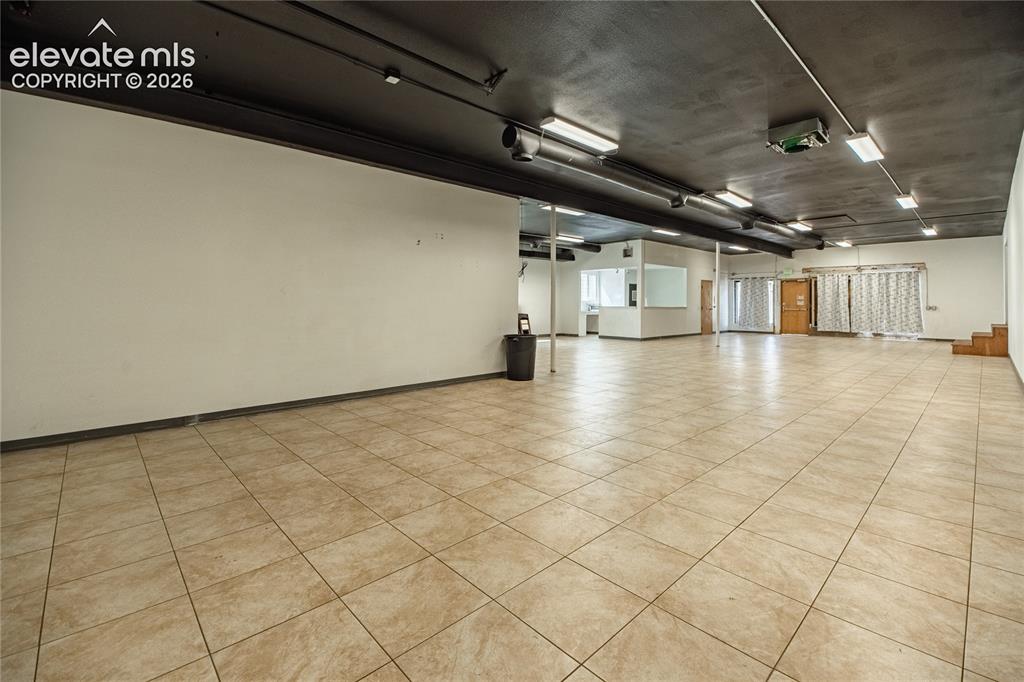 Image 24 of 50: Expansive open-concept space featuring ceramic tile flooring, exposed ductw