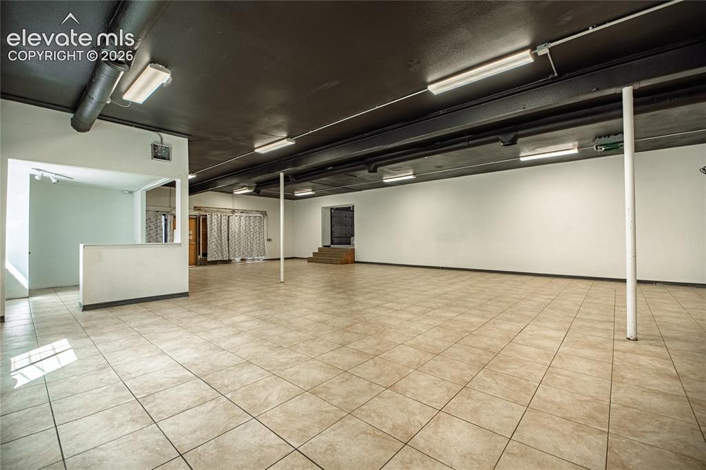 Image 26 of 50: Expansive open space featuring ceramic tile flooring, a painted black ceili
