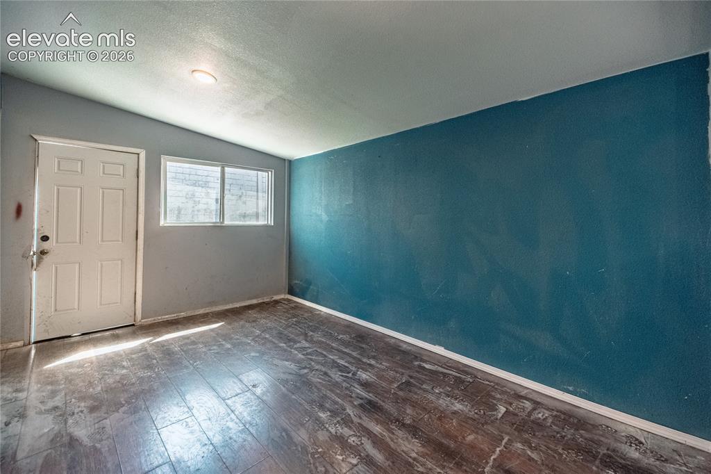 Image 36 of 50: Wood-finish flooring with a multi-pane window, white paneled door, and rece