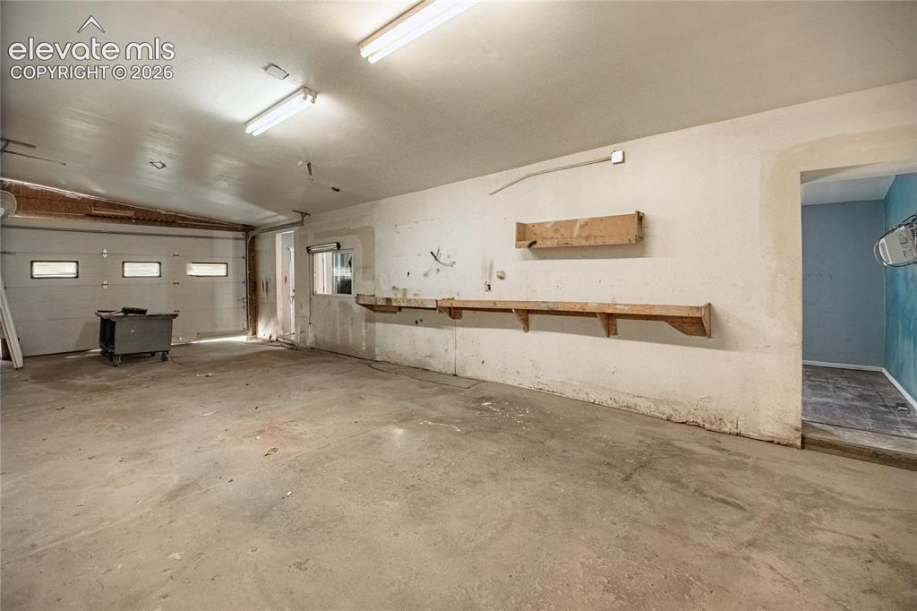 Image 41 of 50: Spacious garage featuring a concrete floor, overhead fluorescent lighting,