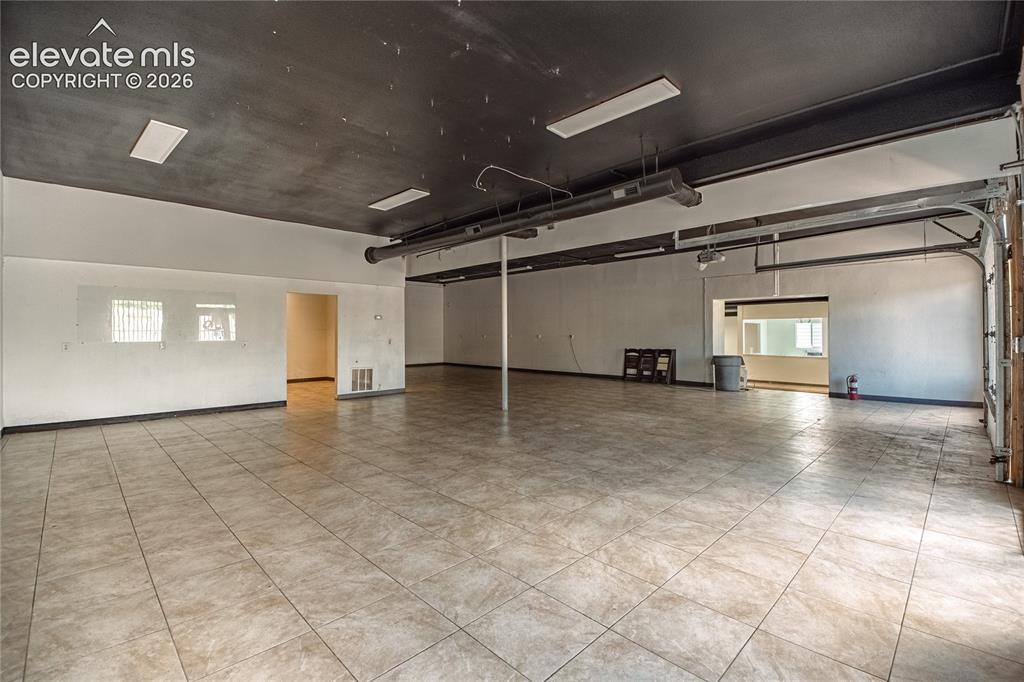 Image 7 of 50: Spacious interior featuring tile flooring, exposed ductwork, recessed light