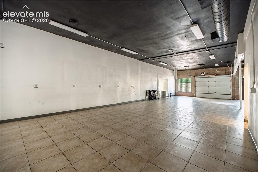 Image 9 of 50: Spacious interior with tiled flooring, exposed ductwork, fluorescent lighti