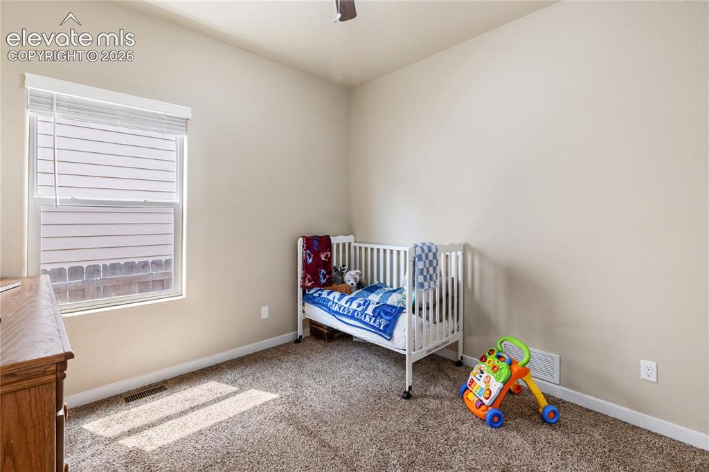 Image 14 of 32: Bright secondary bedroom with a ceiling fan