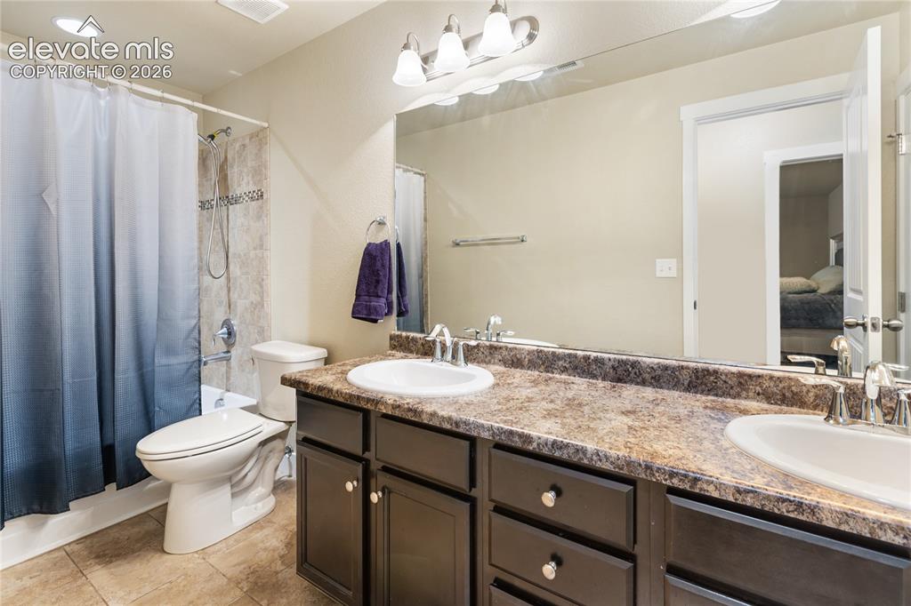 Image 24 of 32: Downstairs bathroom featuring a dual vanity with dark wood-finish cabinetry