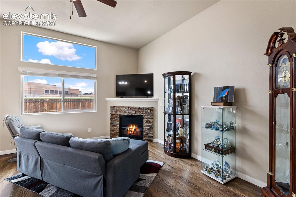 Image 31 of 32: Vaulted ceiling living area featuring wood-finish flooring, a stone-faced f