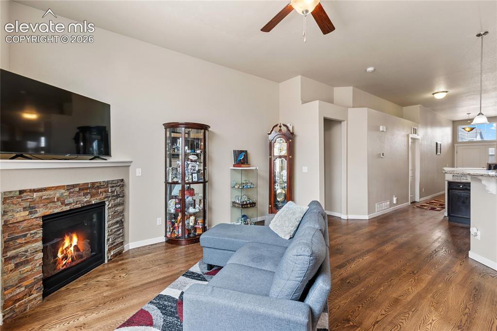 Image 32 of 32: Living area featuring a stacked stone fireplace with a mantel, wood-finish
