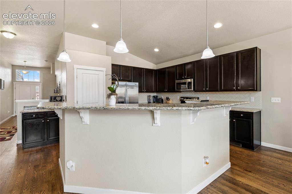 Image 6 of 32: Kitchen featuring warm wood cabinetry, a breakfast bar, and generous counte