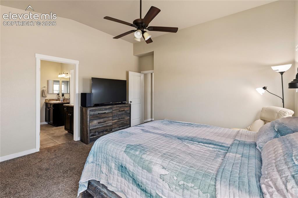 Image 8 of 32: Vaulted ceiling bedroom with a ceiling fan, plush carpet flooring, and a do
