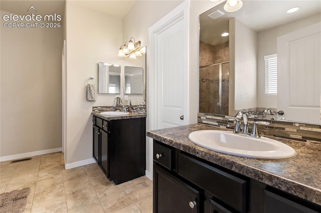 Image 9 of 32: Dual vanity bathroom featuring dark wood cabinetry, integrated oval sinks,