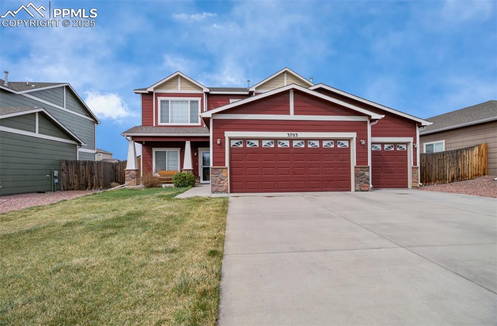 Caption: Craftsman house featuring stone siding, a front yard, fence, and an attached garage