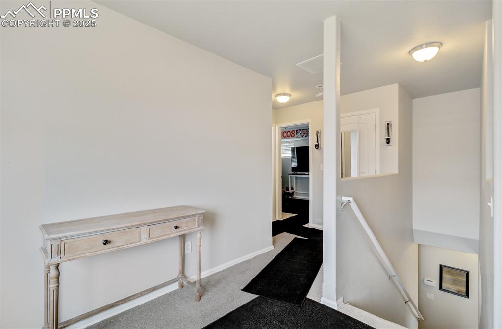 Image 20 of 35: Hallway with baseboards, an upstairs landing, and carpet floors