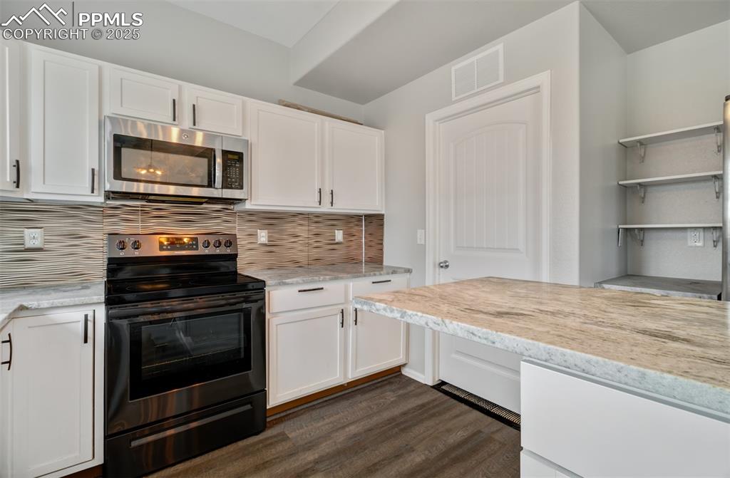 Image 3 of 35: Kitchen featuring white cabinets, visible vents, stainless steel microwave,