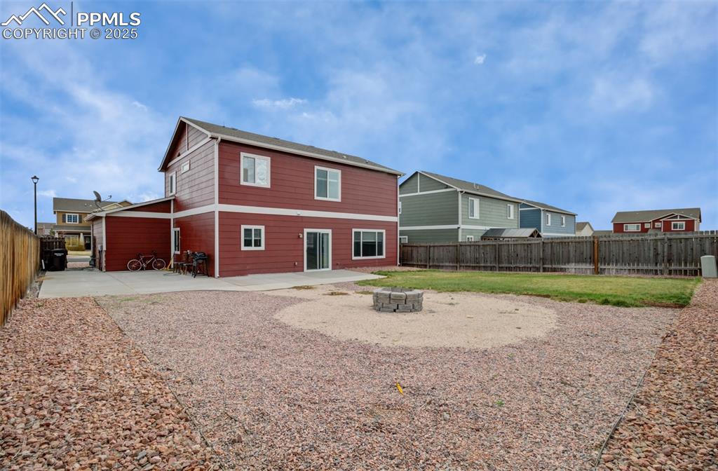 Image 30 of 35: Back of property featuring a fenced backyard, a lawn, a fire pit, and a pat
