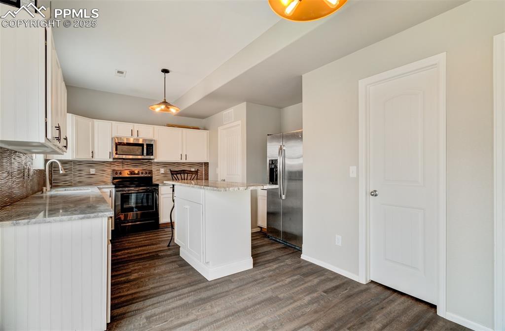 Image 8 of 35: Kitchen with dark wood finished floors, a sink, backsplash, and appliances 