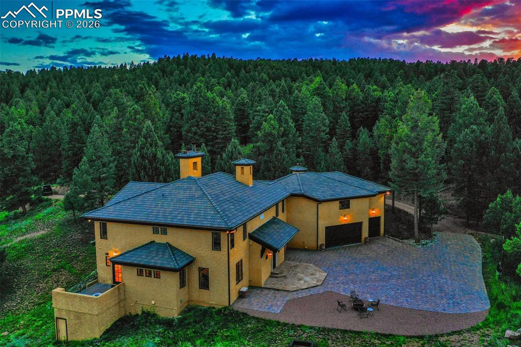 Image 1 of 50: Aerial view at dusk of the structure and front of the home with the paver d