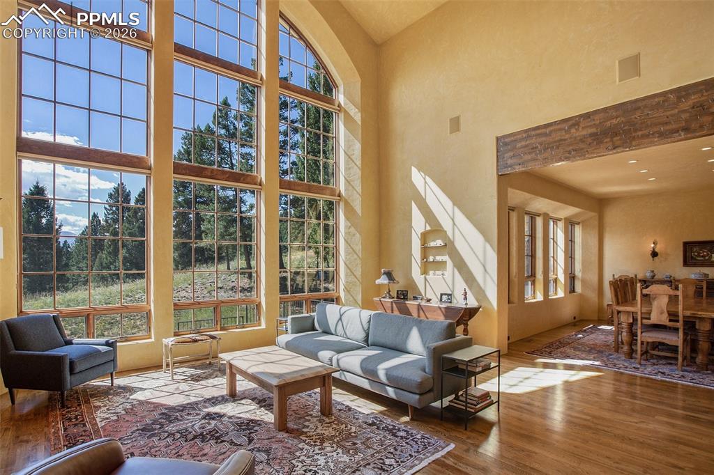 Image 13 of 50: Living room with hardwood flooring and a high ceiling looking into the dini