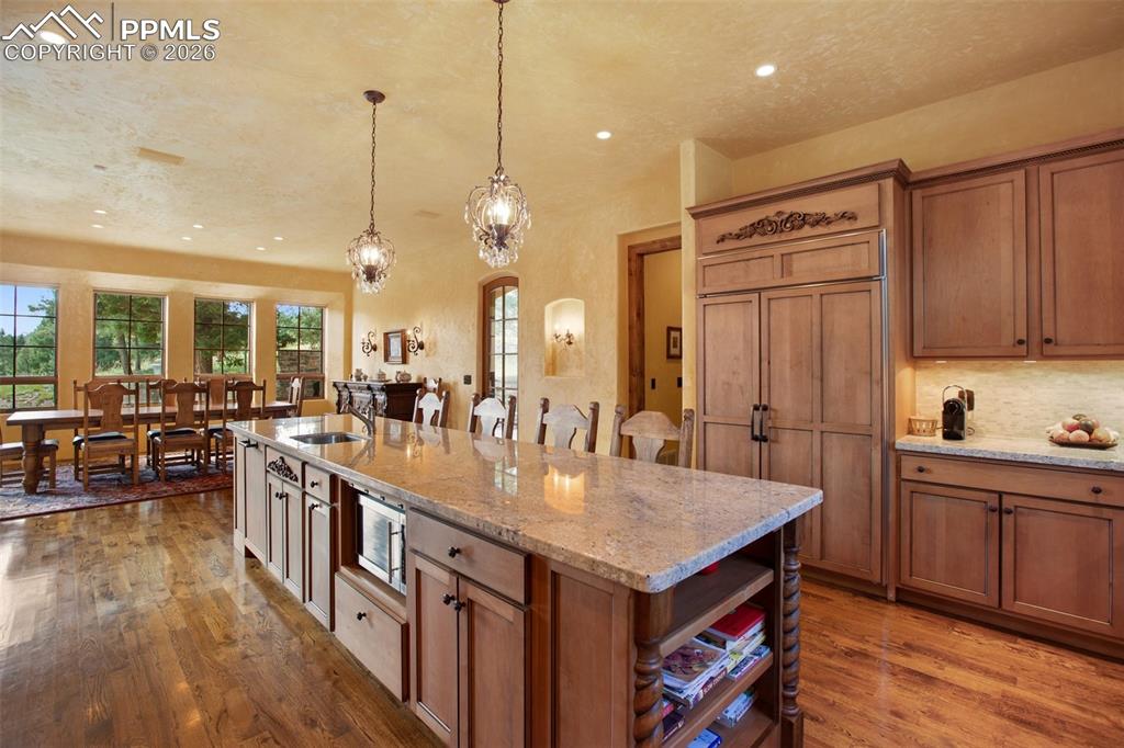 Image 19 of 50: Kitchen with stunning light fixtures, microwave, 48" SubZero Refrigerator a