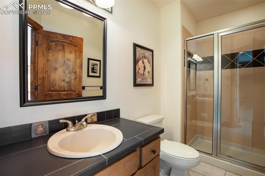 Image 42 of 50: Lower level 3/4 bathroom with black tile countertop and tile floor.