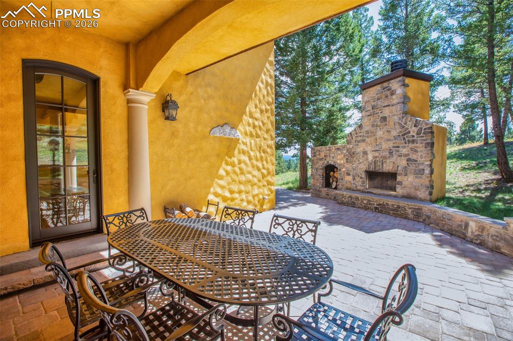 Image 43 of 50: View of patio / terrace with an outdoor stone fireplace and outdoor kitchen