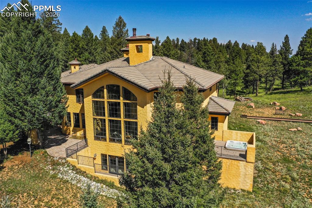 Image 45 of 50: View of back of the home with peak at the national forest beyond the home.