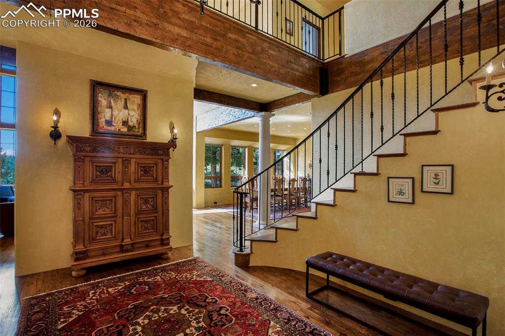 Image 5 of 50: Entryway featuring decorative columns, a towering ceiling, and hardwood flo
