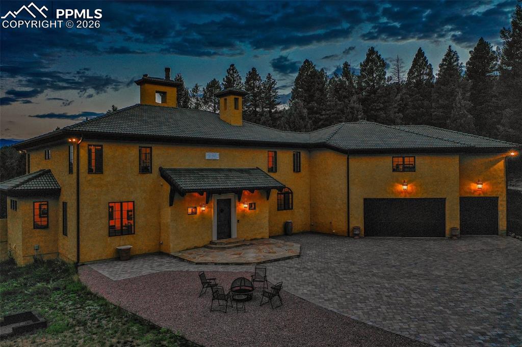 Image 50 of 50: Twilight photo of this beautiful Tuscan-style home featuring the brick pave