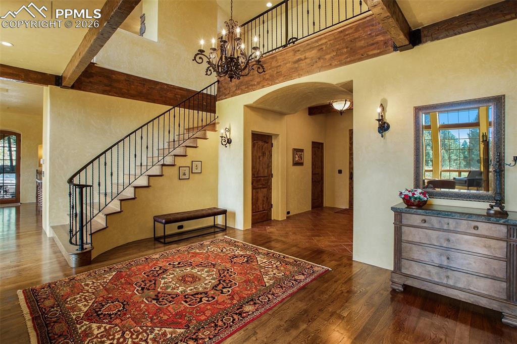 Image 6 of 50: Entryway with beamed ceiling, wood flooring, a towering ceiling, and a nota
