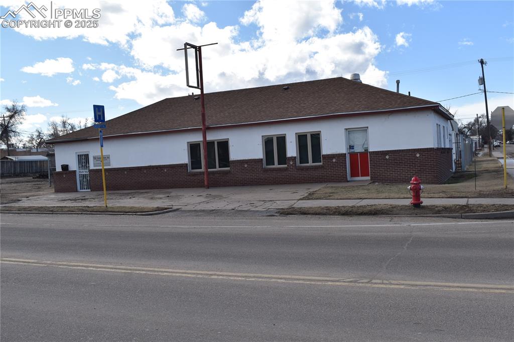 Image 11 of 23: View of front facade with stucco siding, brick siding, and roof with shingl