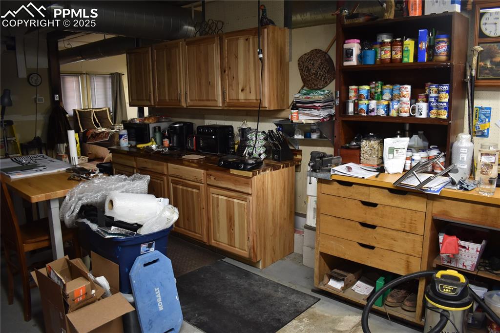 Image 15 of 23: Kitchen with concrete flooring, brown cabinetry, black microwave, and dark