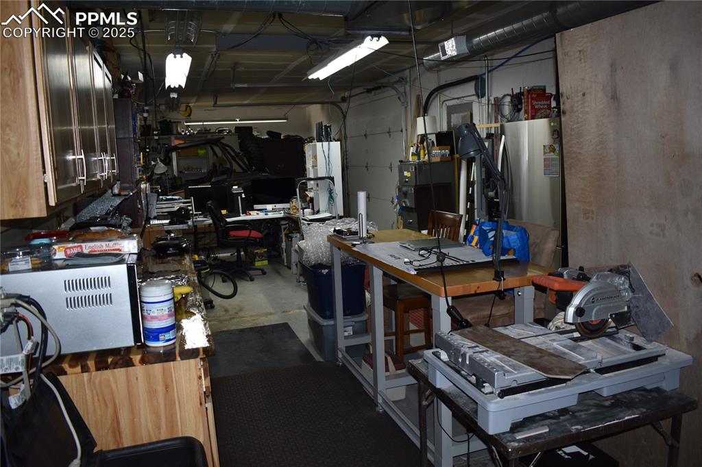 Image 19 of 23: Garage with water heater and a workshop area