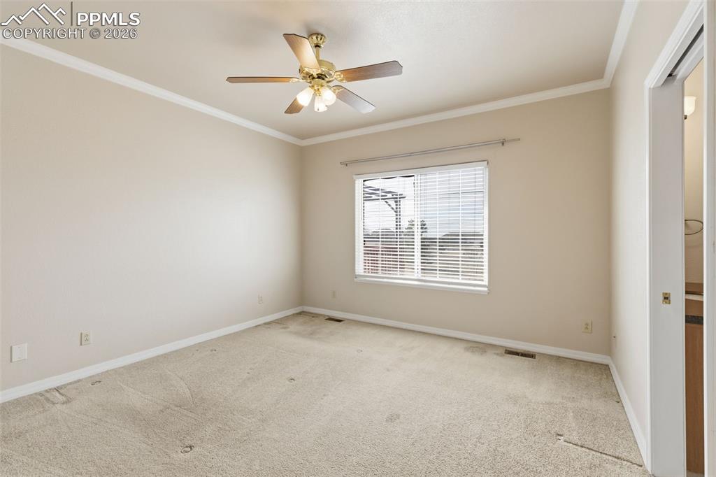 Image 19 of 43: Spare room with ornamental molding, carpet, and a ceiling fan